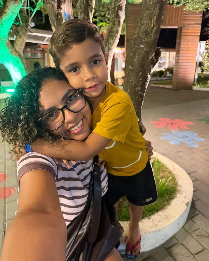 Mariana Lemes sorrindo, abraçada pelo filho José, de 4 anos